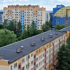 Bloki mieszkalne w różnych kolorach, z zielenią drzew. Zastanawiasz się, o ile można podnieść czynsz za lokal mieszkalny?