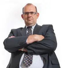 Mężczyzna w garniturze, z założonymi rękami, w okularach. Czy prezes spółdzielni mieszkaniowej jest osobą publiczną?