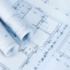 Zrolowane dokumenty z projektem architektoniczno budowlanym, ukazujące plany pomieszczeń i wymiary.