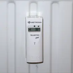 Biały podzielnik ciepła Metrona Telmetric star na grzejniku. Czy podzielniki ciepła są obowiązkowe? Ten pokazuje 387 jednostek.