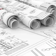 Zwoje dokumentacji technicznej, ukazujące szczegółowe plany budowlane. To projekt zamienny po zakończeniu budowy, gotowy do analizy.