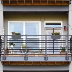 Nowoczesny balkon dostawny do domu jednorodzinnego z meblami i kwiatami.