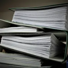 Stosy dokumentów w segregatorach. Zastanawiasz się, jak wydrukować księgę wieczystą? Te papiery mogą zawierać odpowiedzi.