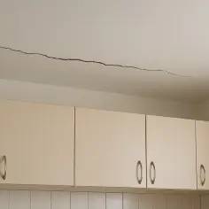 Długie pęknięcie na suficie nad szafkami kuchennymi. Wskazuje na potencjalną odpowiedzialność dewelopera za pęknięcia ścian i stropów.