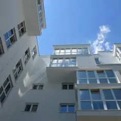 Nowoczesne bloki z wieloma oknami, idealne na mieszkania na licytacji komorniczej. Jasna elewacja i błękitne niebo.