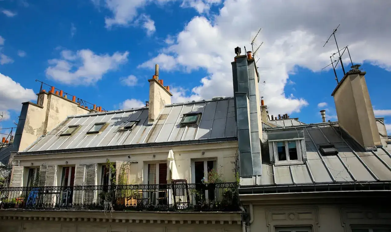 Dachówki, kominy i balkon z meblami. Czy balkon to część wspólna? W Paryżu często tak bywa.