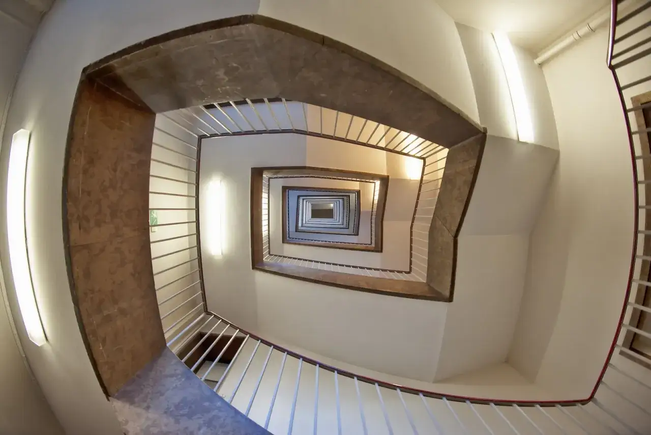 Widok z góry na spiralne schody, gdzie każdy stopień symbolizuje udział w nieruchomości wspólnej.