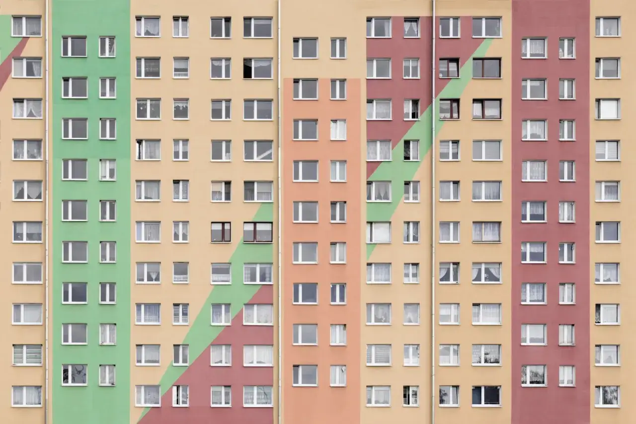Wielopiętrowy blok z kolorowymi pasami. Szukasz informacji, jak dostać mieszkanie od spółdzielni?