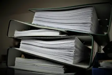Stosy dokumentów w segregatorach. Zastanawiasz się, jak wydrukować księgę wieczystą? Te papiery mogą zawierać odpowiedzi.